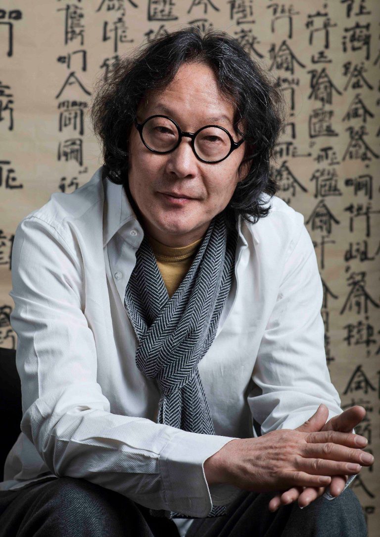 Xu Bing stands in front of his installation "Book from the Sky," surrounded by hand-printed scrolls filled with nonsensical characters.