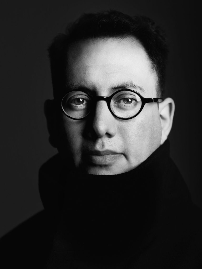 Refik Anadol standing in front of a data visualization installation, showcasing his pioneering work in data-driven art and machine intelligence.
