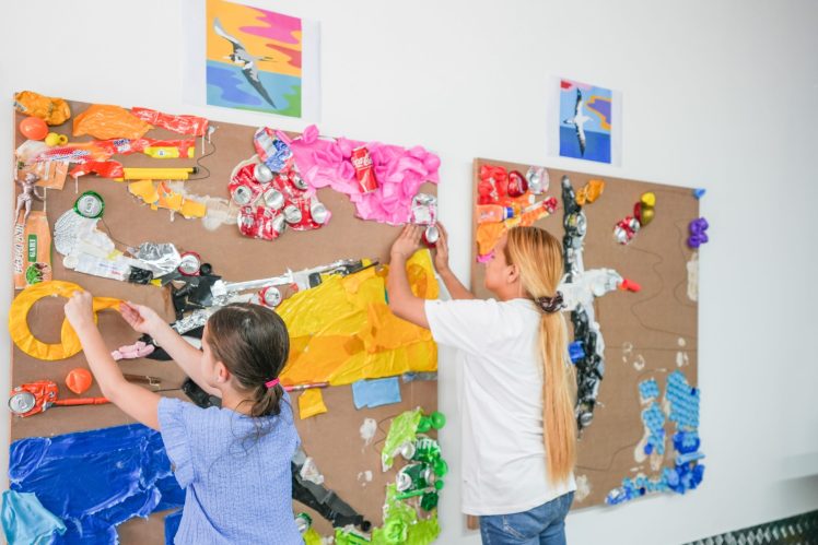 Recycled plastic mural in Dubai's Sustainable City, created by residents and students for Plastic Free July, displayed on a community wall.