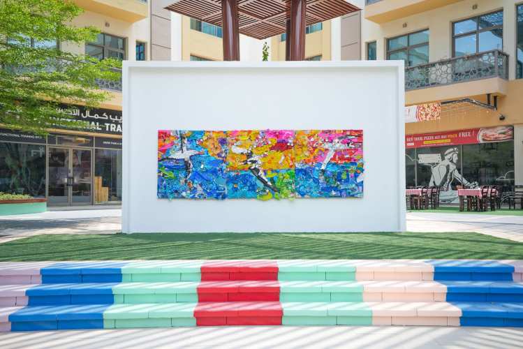 Recycled plastic mural in Dubai's Sustainable City, created by residents and students for Plastic Free July, displayed on a community wall.