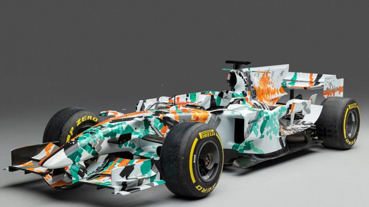 The 2008 Force India VJM01 art car, featuring a green, white, and orange livery designed by Dexter Brown, on display at the Goodwood Festival of Speed.