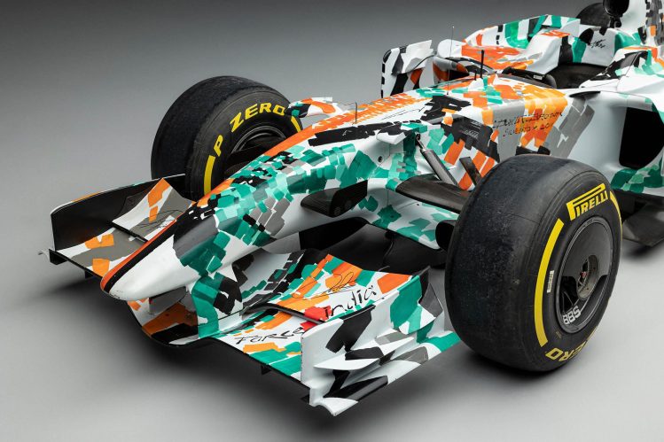 The 2008 Force India VJM01 art car, featuring a green, white, and orange livery designed by Dexter Brown, on display at the Goodwood Festival of Speed.