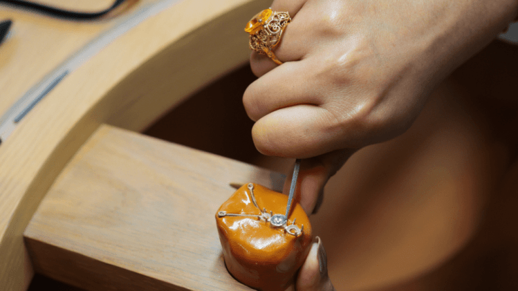 A jewelry artisan carefully shaping a gold ring while examining the details at L’ÉCOLE Middle East.